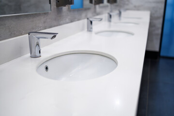 water faucet automatic, white ceramic surface in a public toilet