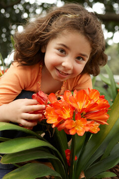 Little girl holding a bunch (umbels) of clivia miniata (bush lily) yellow orange flowers.