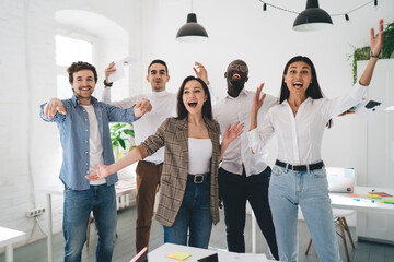 Happy multiethnic coworkers rejoicing over success while throwing papers in air