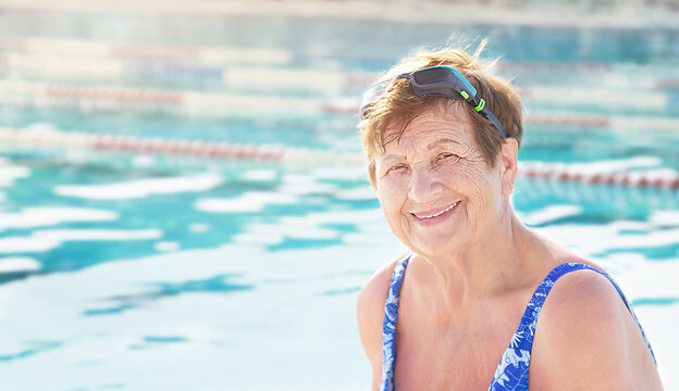 Active senior (elderly) woman (over age of 50) in sport goggles and swimsuit near swimming pool. Healthy lifestyle.
