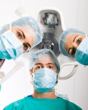 Team of medical professionals looking down at patient in surgical theater