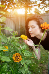Obraz na płótnie Canvas pretty brunette female smelling bloom yellow flowers in garden outdoors