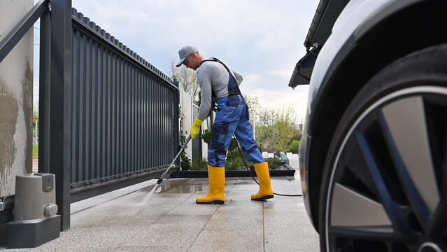 Man Pressure Washing Concrete Slab Driveway