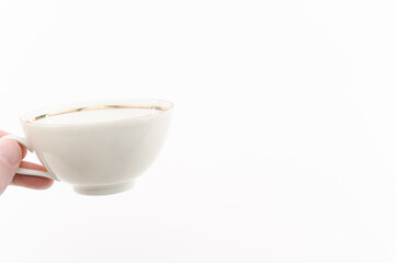 immagine primo piano di mano che regge elegante tazza in porcellana da tè in stile classico su sfondo bianco