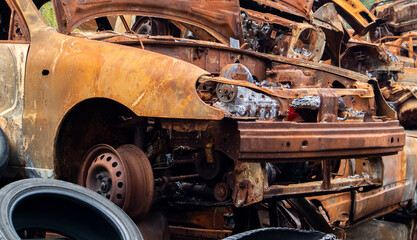 Fototapeta premium A lot of burnt fired cars in the parking lot, the consequences of the invasion of Ukraine. War in Ukraine. Cemetery of destroyed cars of civilians who tried to evacuate from the war zone.