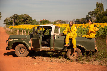 Duas apicultoras em uma caminhonete, parada em uma estrada de chão, visitando uma plantação de...