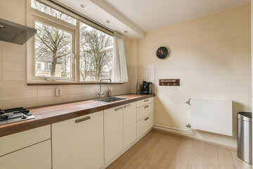 a kitchen with wood counter tops and white cabinets in front of the window that looks out to the trees outside