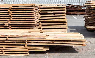 Pile of stacked wooden planks at a construction site. Wooden boards, lumber. Industrial edged timber. Wooden rafters for the repair or construction of a private house. Roofing and joinery lumber.