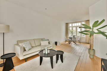 a living room with white walls and hardwood flooring, there is a large plant in the center of the room