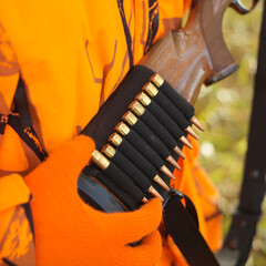 Close-up of hunter removing bullet from ammo holder on rifle.