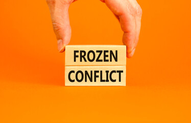 Frozen conflict symbol. Concept words Frozen conflict on beautiful wooden block. Beautiful orange table orange background. Businessman hand. Business and Frozen conflict concept. Copy space.