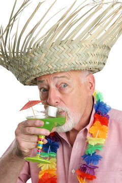 A senior man on a tropical vacation drinking a margarita with a surprised expression.  Isolated.