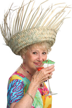 A beautiful senior lady enjoying a tropical cocktail on a cruise.  Isolated.