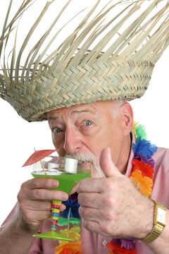 A senior man on a tropical vacation drinking a margarita and giving a thumbs up.