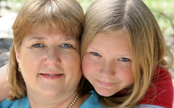 Closeup portrait of a pretty blond, blue-eyed mother and daughter.