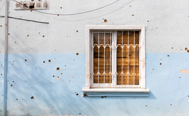 The buildings were hit by shelling. Boarded up windows and damaged facade. Preparing the house for hostilities and war. Destroyed houses in the city during the war in Ukraine.