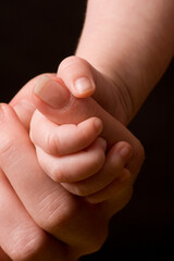 Small baby hand holding mothers finger