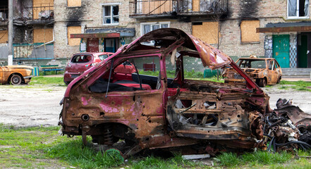 The car that burned down after the bombing of the city stands in the courtyard of a destroyed...