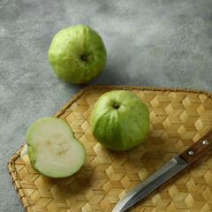 guava fruit, which is cut with a knife on a bamboo mat.