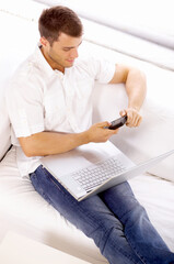 Young man sitting on couch and working on laptop