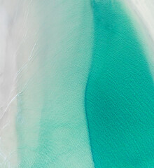 Aerial view of a beach with nice waves and shades of blues. Beautiful beach and scenes