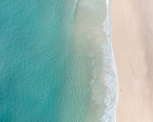 Aerial view of a beach with nice waves and shades of blues. Beautiful beach and scenes