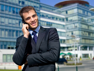 Portrait of business man outside the building using cell phone