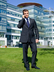 Portrait of business man outside the building using cell phone