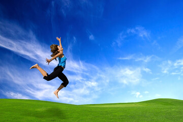 Beautiful athletic woman jumping on a green meadow