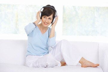 Young woman on couch and listen to the music