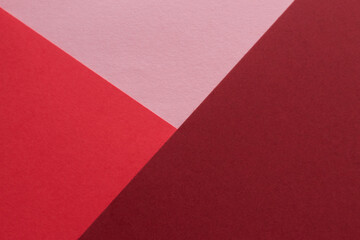 Paper in three shades of red lies on the table, creating a geometric composition