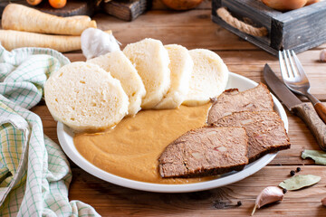 Svickova na smetane ( beef in sour cream sauce) served with knedlik (bread dumpling) on the table, traditional Czech cuisine