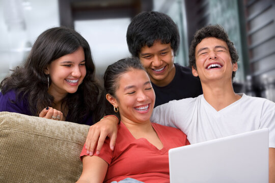Teenagers watching something interesting on laptop at home.