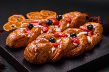 Delicious fresh crispy pastry in the form of a pigtail with strawberries and blueberries