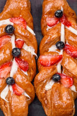 Delicious fresh crispy pastry in the form of a pigtail with strawberries and blueberries