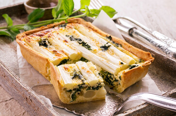 Traditional French vegetable tarte with asparagus and spinach served as close-up on a stone tray