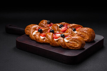 Delicious fresh crispy pastry in the form of a pigtail with strawberries and blueberries