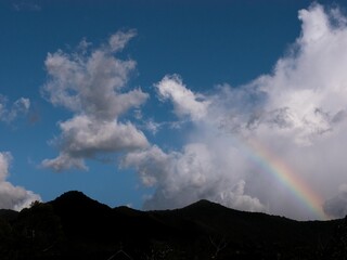 silhouette of mountain with rainbow and clouds