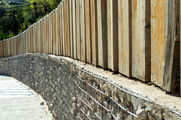 Wooden fence on a stone base with metal mesh