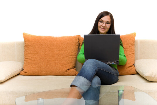 attractive brunette woman sitting on sofa with laptop