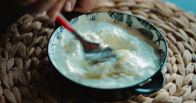 Making yoghurt with garlic. Garlic is grated into yogurt and mixed.