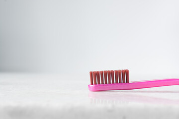 Pink toothbrush with orange bristles on a white background, pink toothbrush with copy space - Powered by Adobe