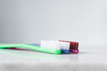 Blue, pink and green toothbrush with white bristles on a white background, colorful toothbrushes with copyspace
