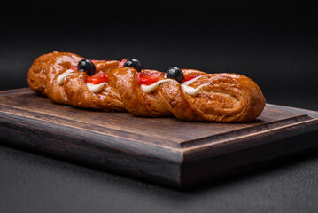 Delicious fresh crispy pastry in the form of a pigtail with strawberries and blueberries