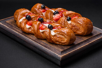 Delicious fresh crispy pastry in the form of a pigtail with strawberries and blueberries