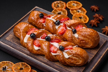 Delicious fresh crispy pastry in the form of a pigtail with strawberries and blueberries