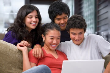 Teenagers watching something interesting on laptop at home.