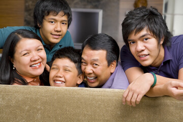 Happy Asian family in the livingroom gazing to camera.