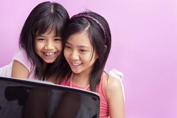 Little girls playing laptop in the bedroom with pink copy space
