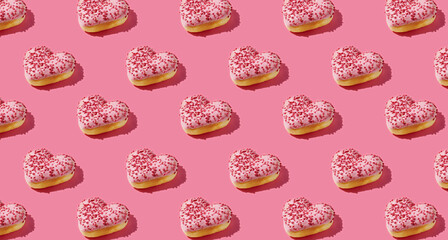 Pattern of heart shaped pink donut with glaze on pink pastel background